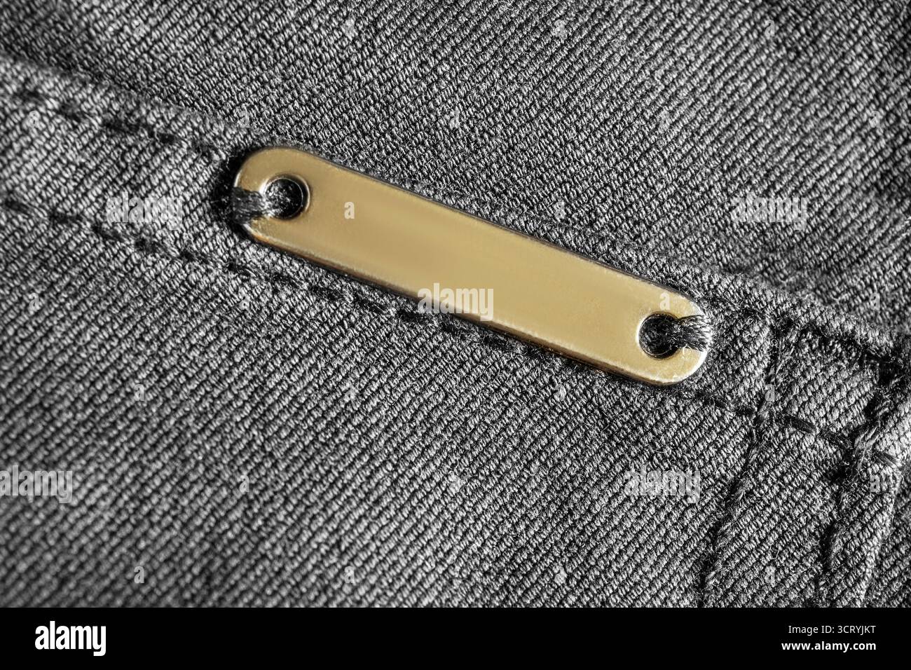 Leeres Namensschild aus Metall auf schwarzem Denim-Hintergrund Stockfoto