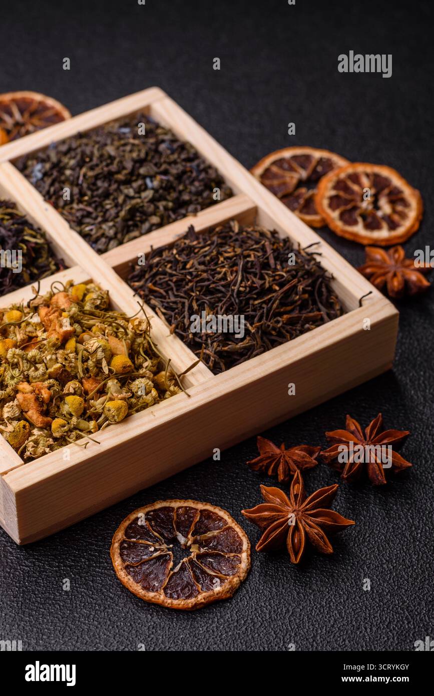 Eine Holzkiste mit verschiedenen Arten von getrocknetem Tee, grünem, schwarzem, Obst und Kamille. Trockener Tee in der Box als Hintergrund für Ihr Design. Stockfoto