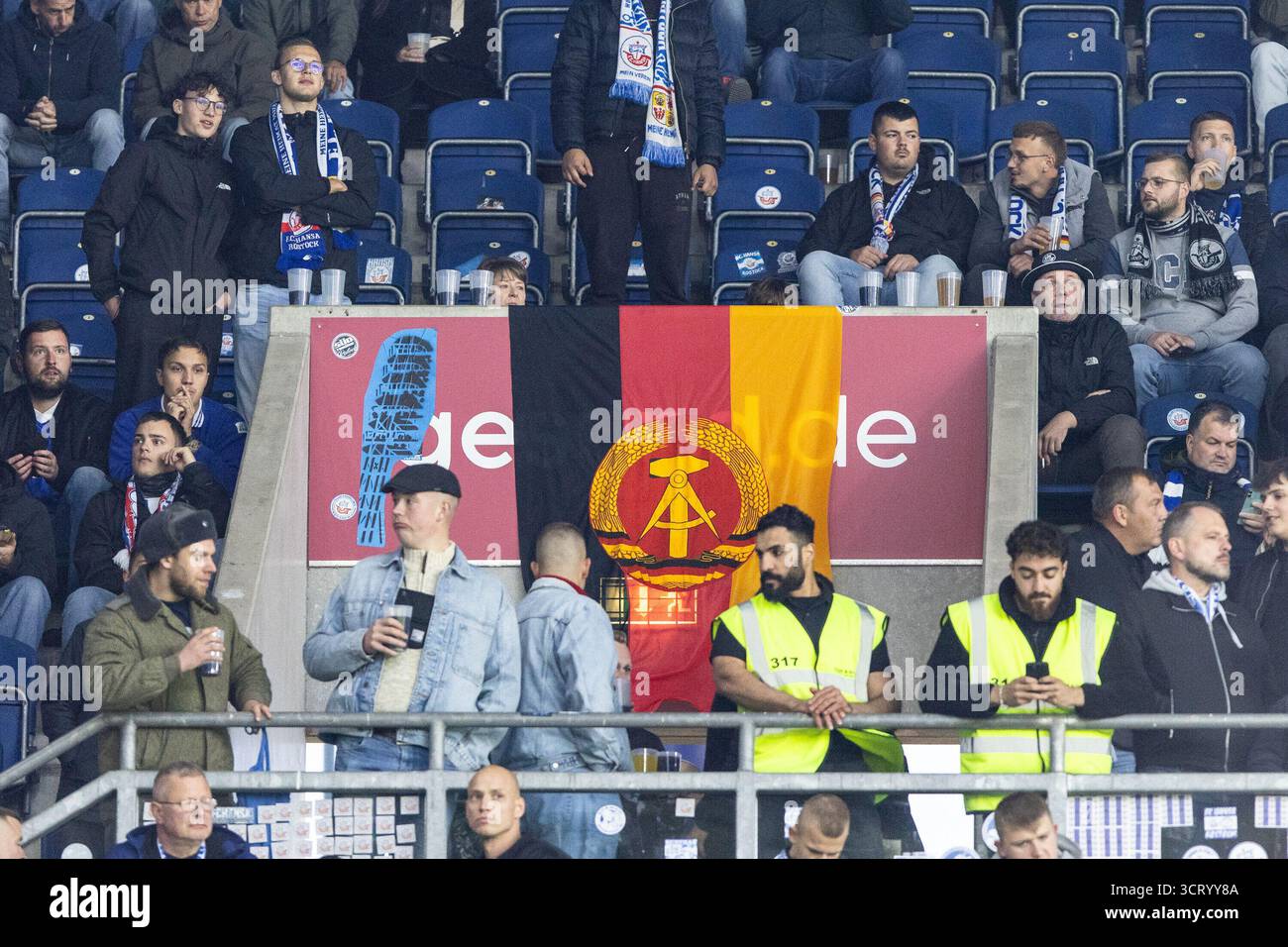 Duisburg, Deutschland. Oktober 2025. Fans von FC Hansa Rostock, Flagge mit dem Logo von DDR (Deutsche Demokratische Republik). 3.Liga 10.Spieltag: MSV Duisburg - FC Hansa Rostock; Schauinsland-Reisen-Arena, Duisburg; 03.10.2025 DFB-Vorschriften verbieten jede Verwendung von Fotografien als Bildsequenzen und/oder Quasi-Video. Quelle: dpa/Alamy Live News Stockfoto