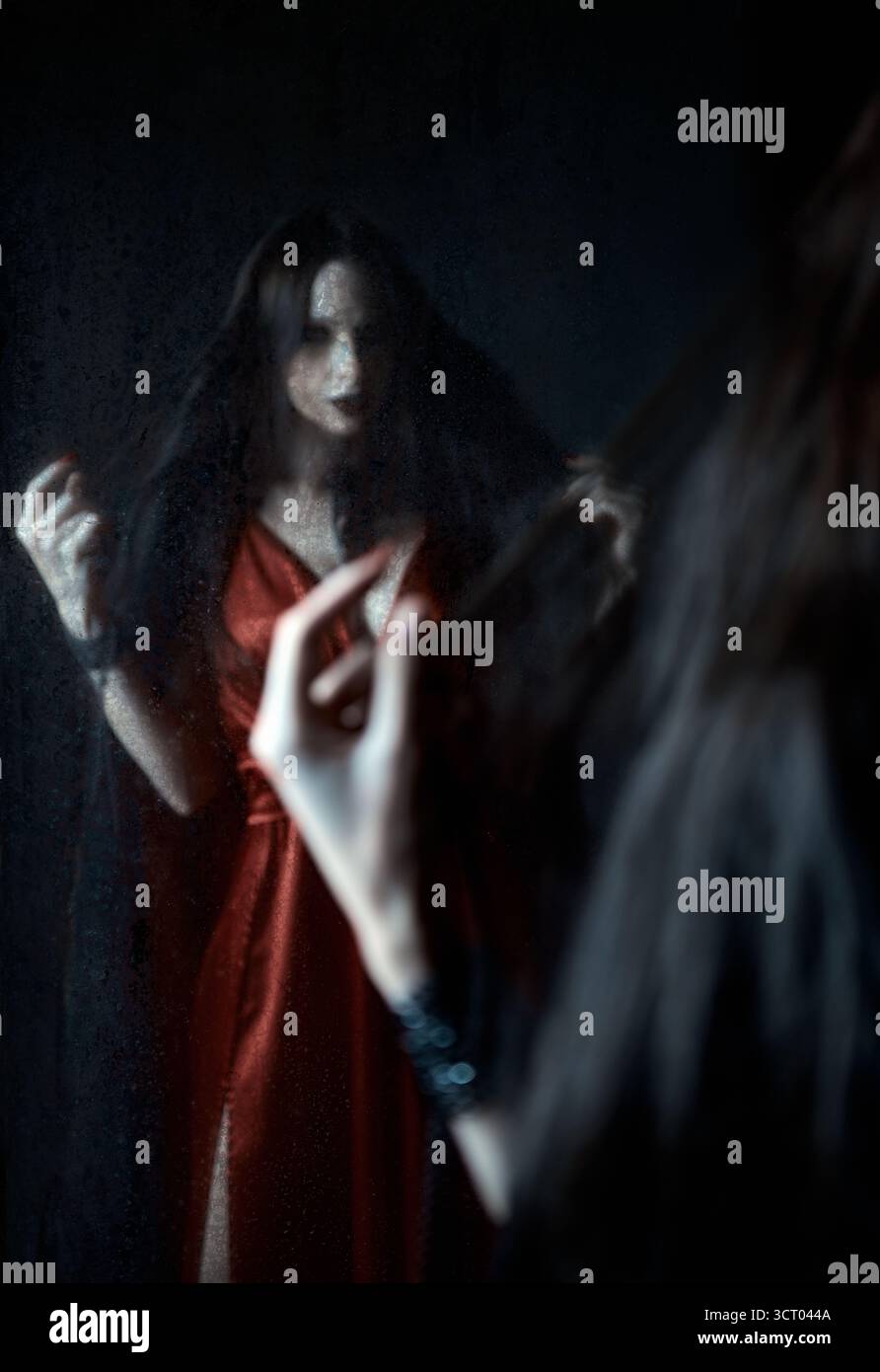 Horrorszene: Verschwommenes Spiegelbild des Geistermädchens im alten schmutzigen Spiegel. Porträt der Vampirfrau Stockfoto