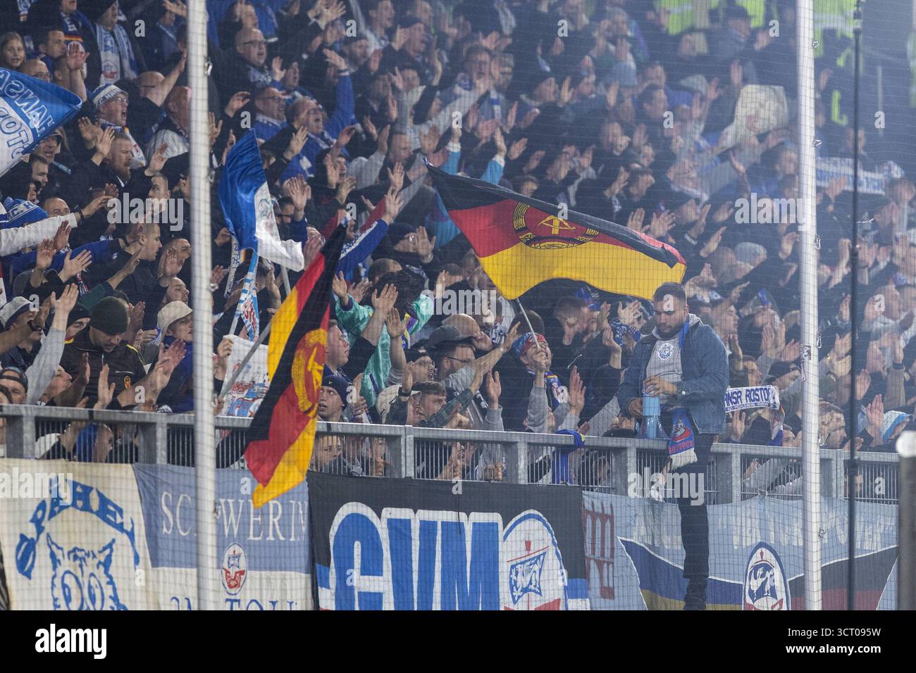 Duisburg, Deutschland. Oktober 2025. Fans von FC Hansa Rostock, Flagge mit dem Logo von DDR (Deutsche Demokratische Republik). 3.Liga 10.Spieltag: MSV Duisburg - FC Hansa Rostock; Schauinsland-Reisen-Arena, Duisburg; 03.10.2025 DFB-Vorschriften verbieten jede Verwendung von Fotografien als Bildsequenzen und/oder Quasi-Video. Quelle: dpa/Alamy Live News Stockfoto