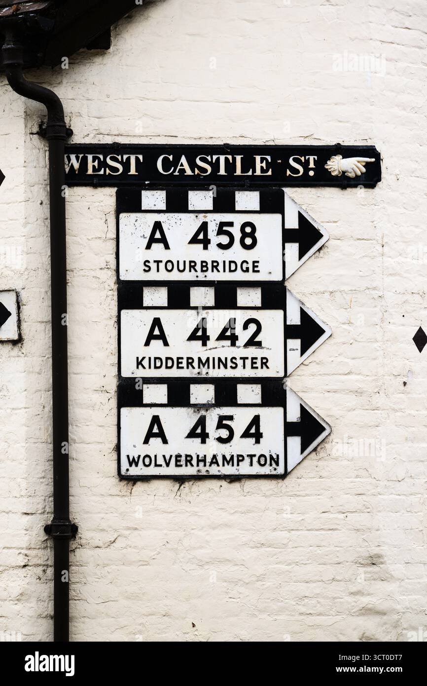 Traditionelle britische Hauptverkehrsschilder an der weißen Backsteinmauer im Pre-Worboys-Stil Stockfoto
