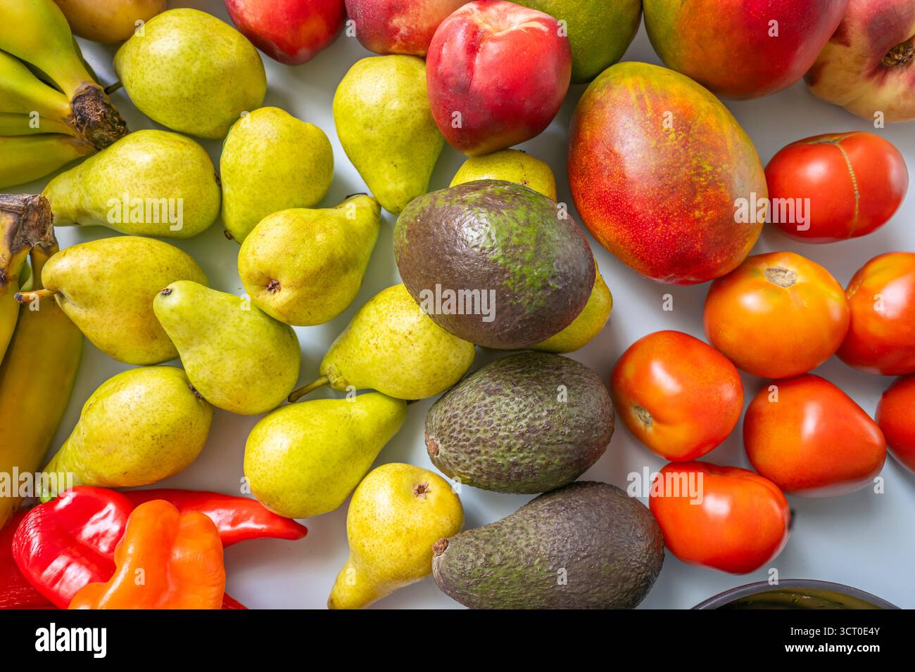 Minimalistisches Stillleben, wo Bananen, Birnen, Avocados, Kartoffeln, Nektarinen, und Feigen erzeugen einen Regenbogen aus Farben auf einem blassblauen Hintergrund Stockfoto