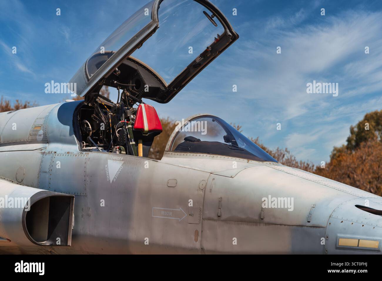 Militärflugzeug mit offenem Cockpit auf dem Landebahnstreifen, blauer Himmel und Busch hinten, afrikanische Luftfahrt Stockfoto