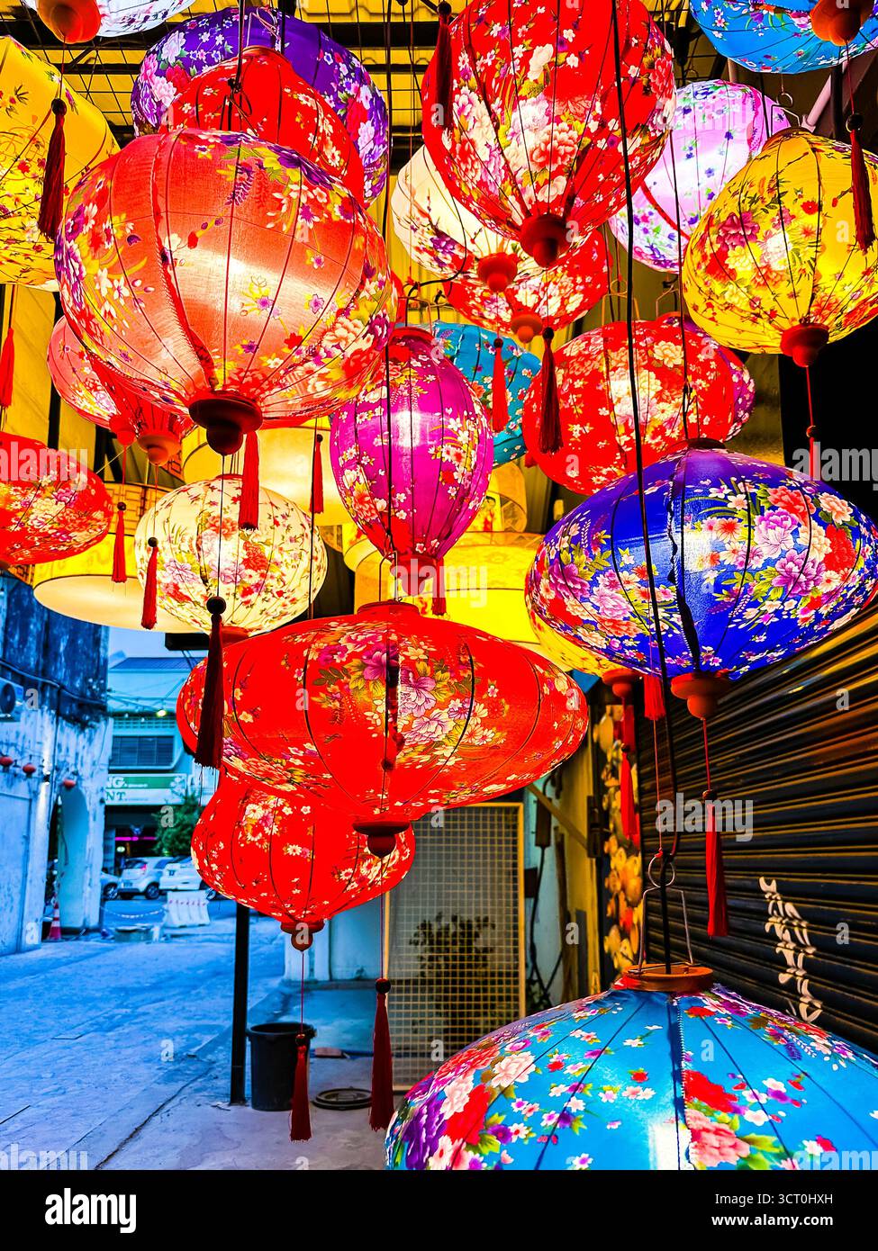 Farbenfrohe Laternen mit Blumenmuster hängen in einer Reihe auf einem Straßenmarkt während einer Festivalfeier am Abend ipoh malaysia Stockfoto