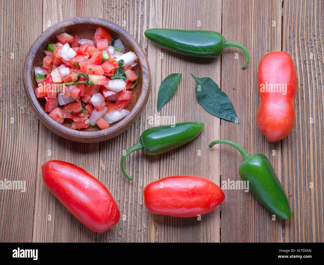 Ein flaches Foto von einer Schüssel Salsa mit ganzen Tomaten und Paprika. Stockfoto