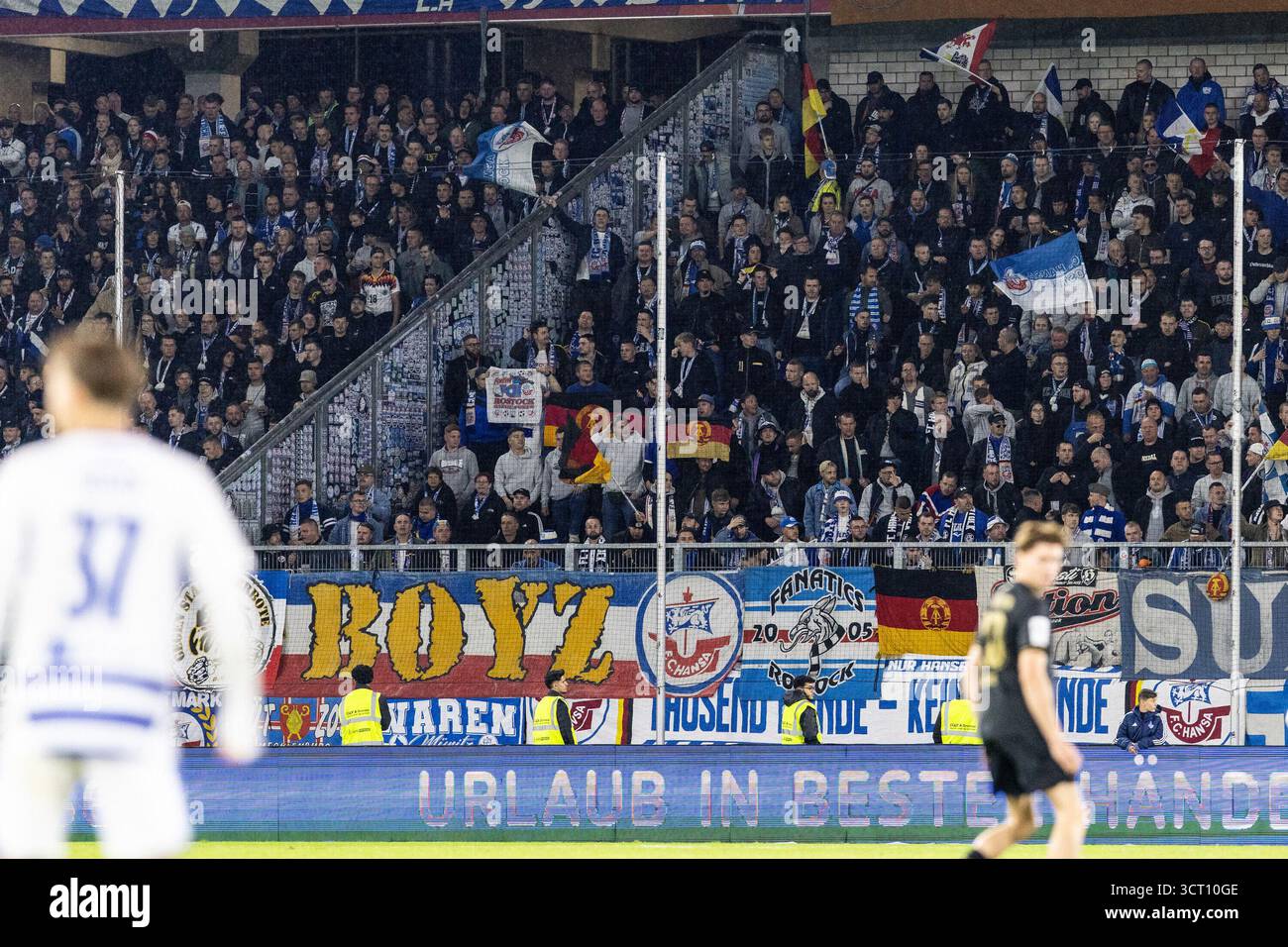 Duisburg, Deutschland. Oktober 2025. Fans von FC Hansa Rostock, Flagge mit dem Logo von DDR (Deutsche Demokratische Republik). 3.Liga 10.Spieltag: MSV Duisburg - FC Hansa Rostock; Schauinsland-Reisen-Arena, Duisburg; 03.10.2025 DFB-Vorschriften verbieten jede Verwendung von Fotografien als Bildsequenzen und/oder Quasi-Video. Quelle: dpa/Alamy Live News Stockfoto
