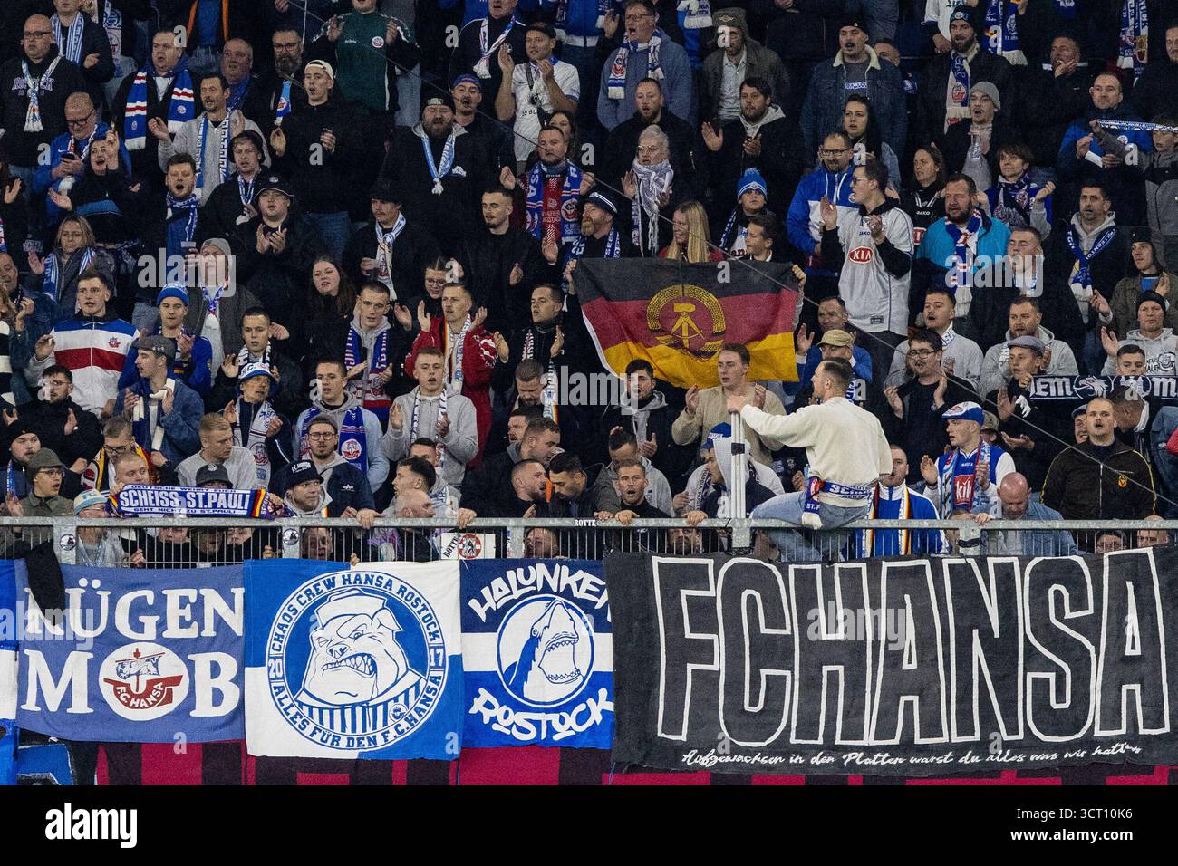 Duisburg, Deutschland. Oktober 2025. Fans von FC Hansa Rostock, Flagge mit dem Logo von DDR (Deutsche Demokratische Republik). 3.Liga 10.Spieltag: MSV Duisburg - FC Hansa Rostock; Schauinsland-Reisen-Arena, Duisburg; 03.10.2025 DFB-Vorschriften verbieten jede Verwendung von Fotografien als Bildsequenzen und/oder Quasi-Video. Quelle: dpa/Alamy Live News Stockfoto