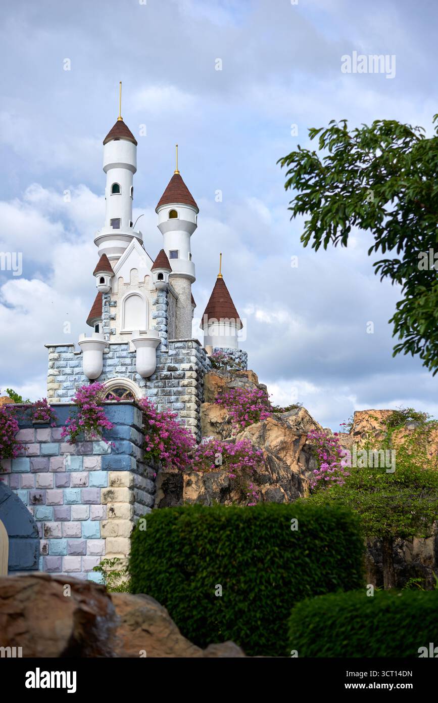 Ein malerisches Schloss mit hohen Türmen und lebendigen Blumen, die die Mauern hinunter ragen. Üppiges Grün umgibt die Struktur und schafft ein ruhiges atmos Stockfoto
