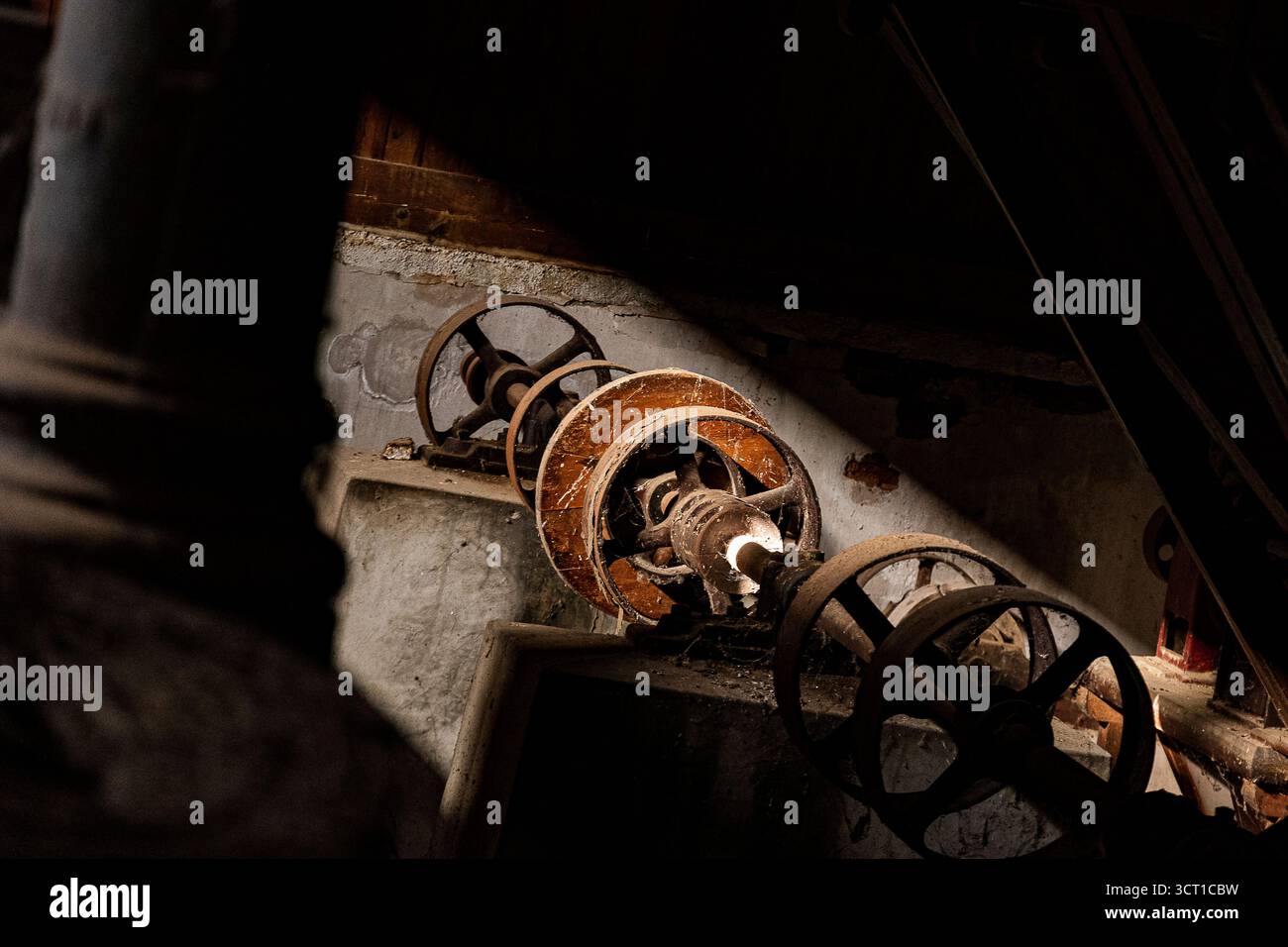 Sonnenlicht zeigt alte, rostige Zahnräder in einer verlassenen industriellen Umgebung und zeigt Überreste vergangener Maschinen. Stockfoto