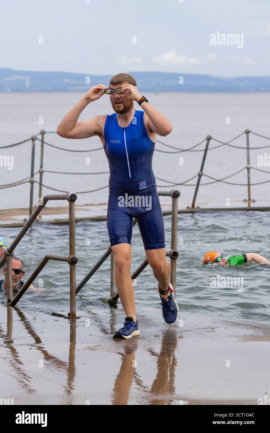 Teilnehmer, die nach dem Schwimmen aus dem See aussteigen Stockfoto