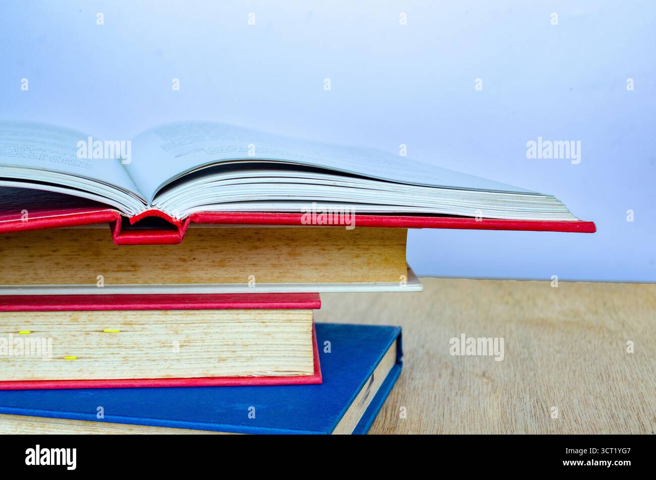 Eine dynamische Anordnung von Büchern, die in einer Hälfte gestapelt sind, mit Seiten in der Mitte des Umlaufs, wodurch ein Bewegungseffekt entsteht Stockfoto