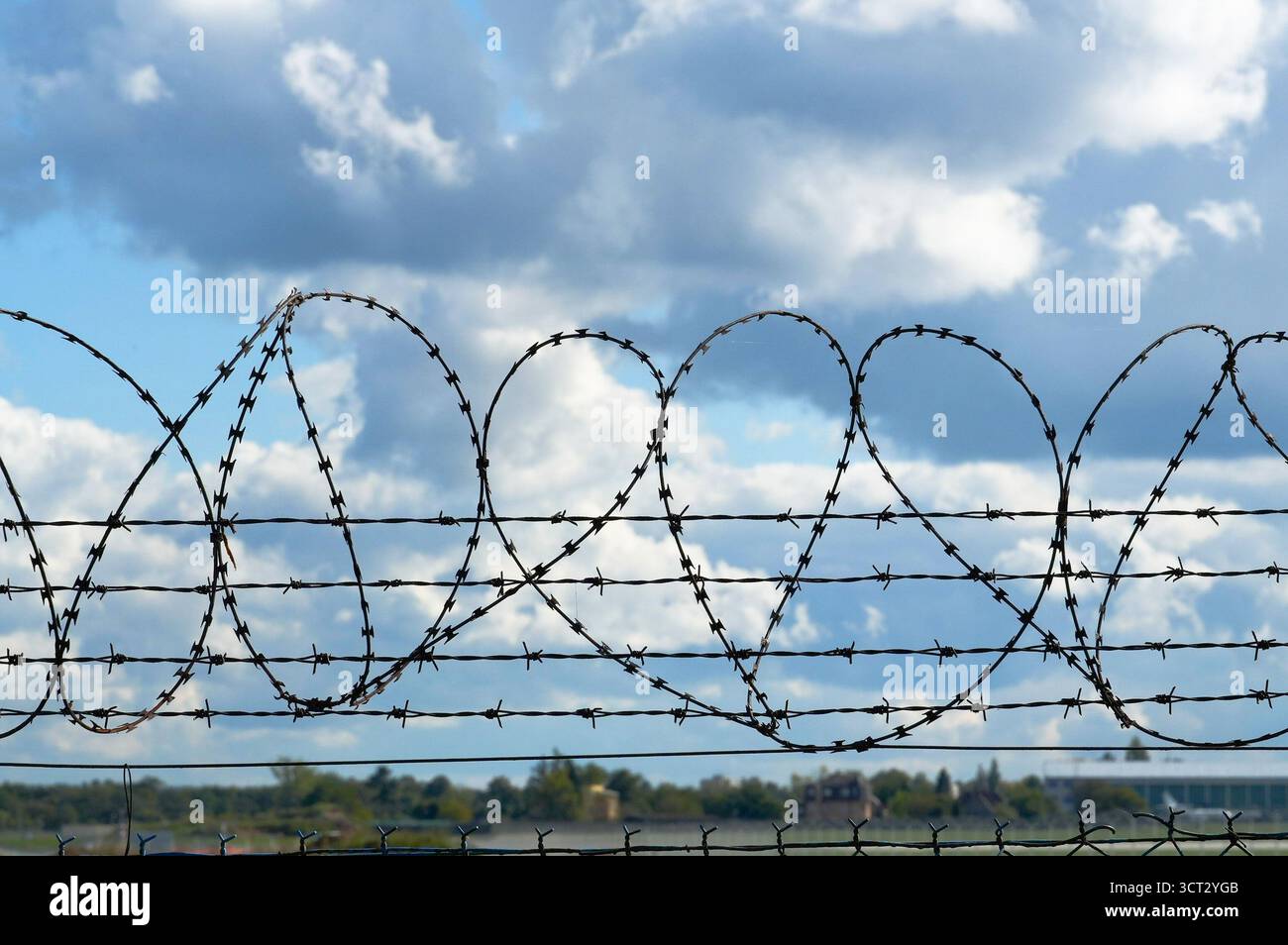 Stacheldraht auf dem Hintergrund des blauen Himmels mit weißen Wolken. Stockfoto