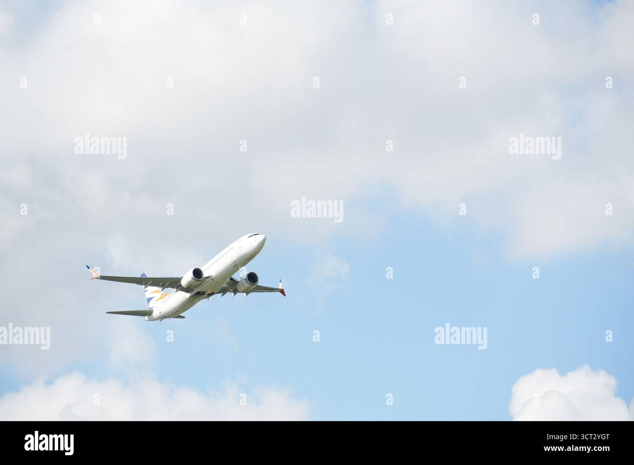 Das Flugzeug fliegt am blauen Himmel mit weißen Wolken an einem sonnigen Tag Stockfoto
