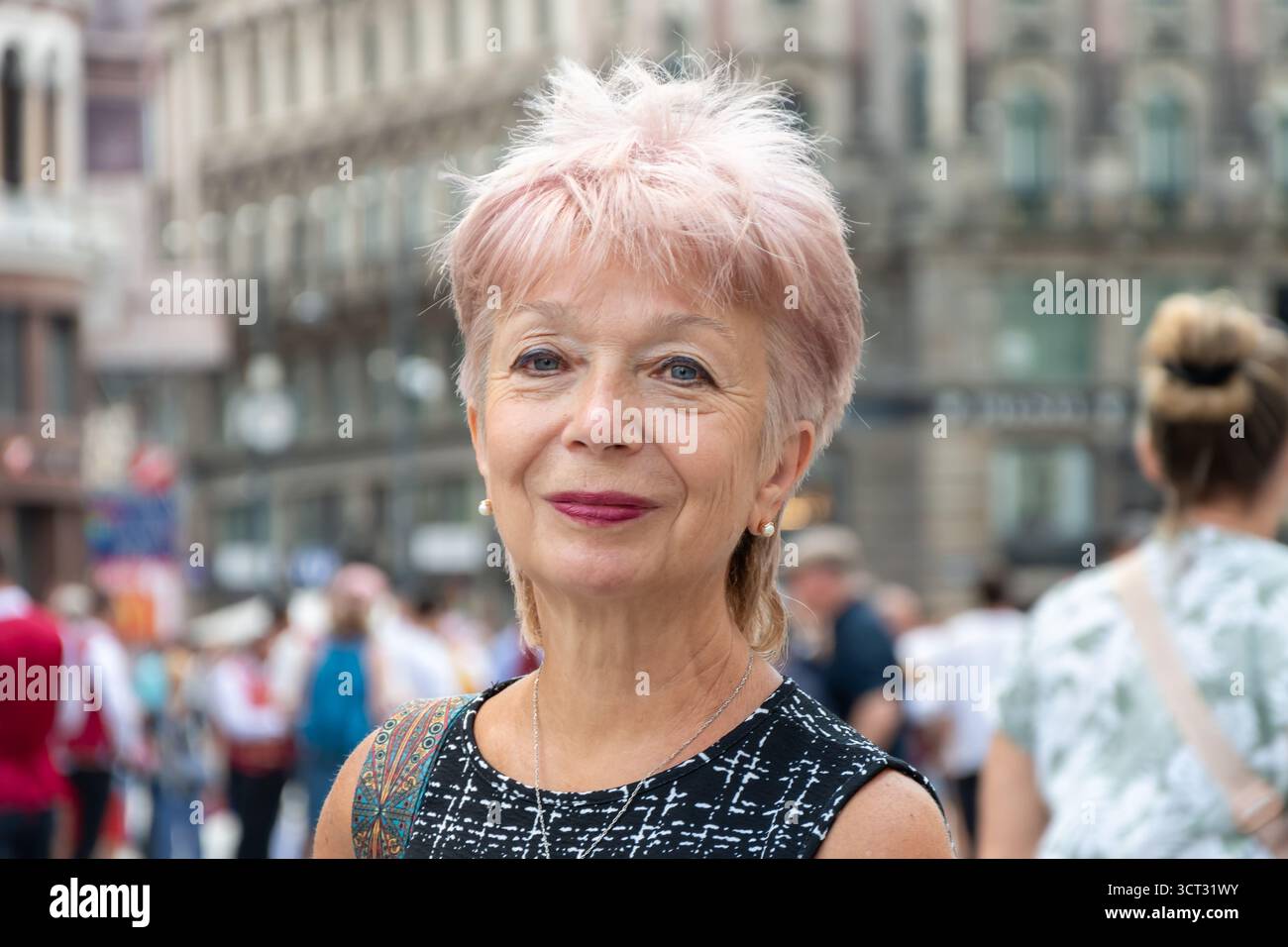 Eine einsame, elegante Frau genießt einen Spaziergang vor der Kulisse der Architektur und der Menschen des historischen Zentrums Stockfoto
