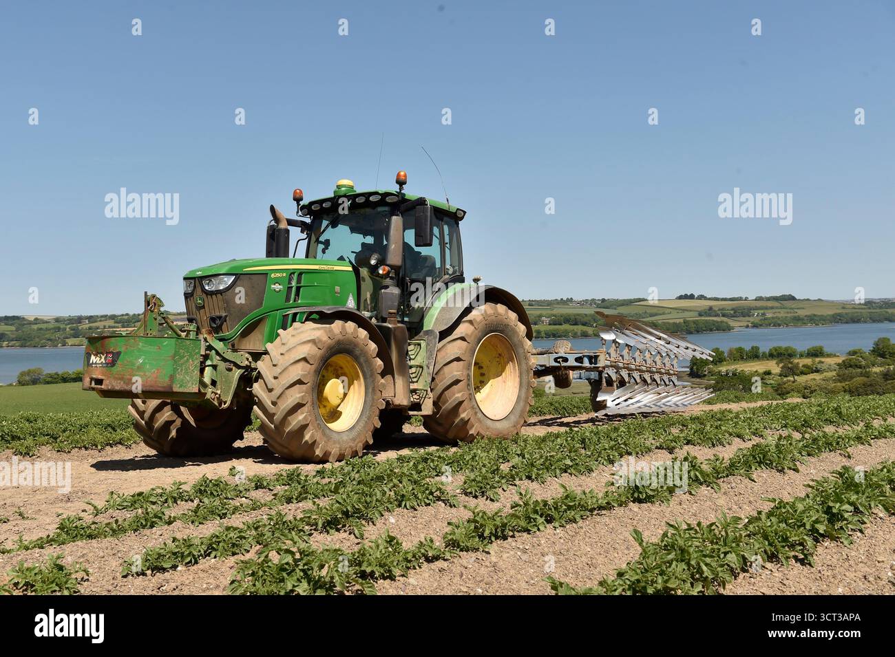 John Deere Traktor mit einem Pflug auf einem Kartoffelfeld Stockfoto