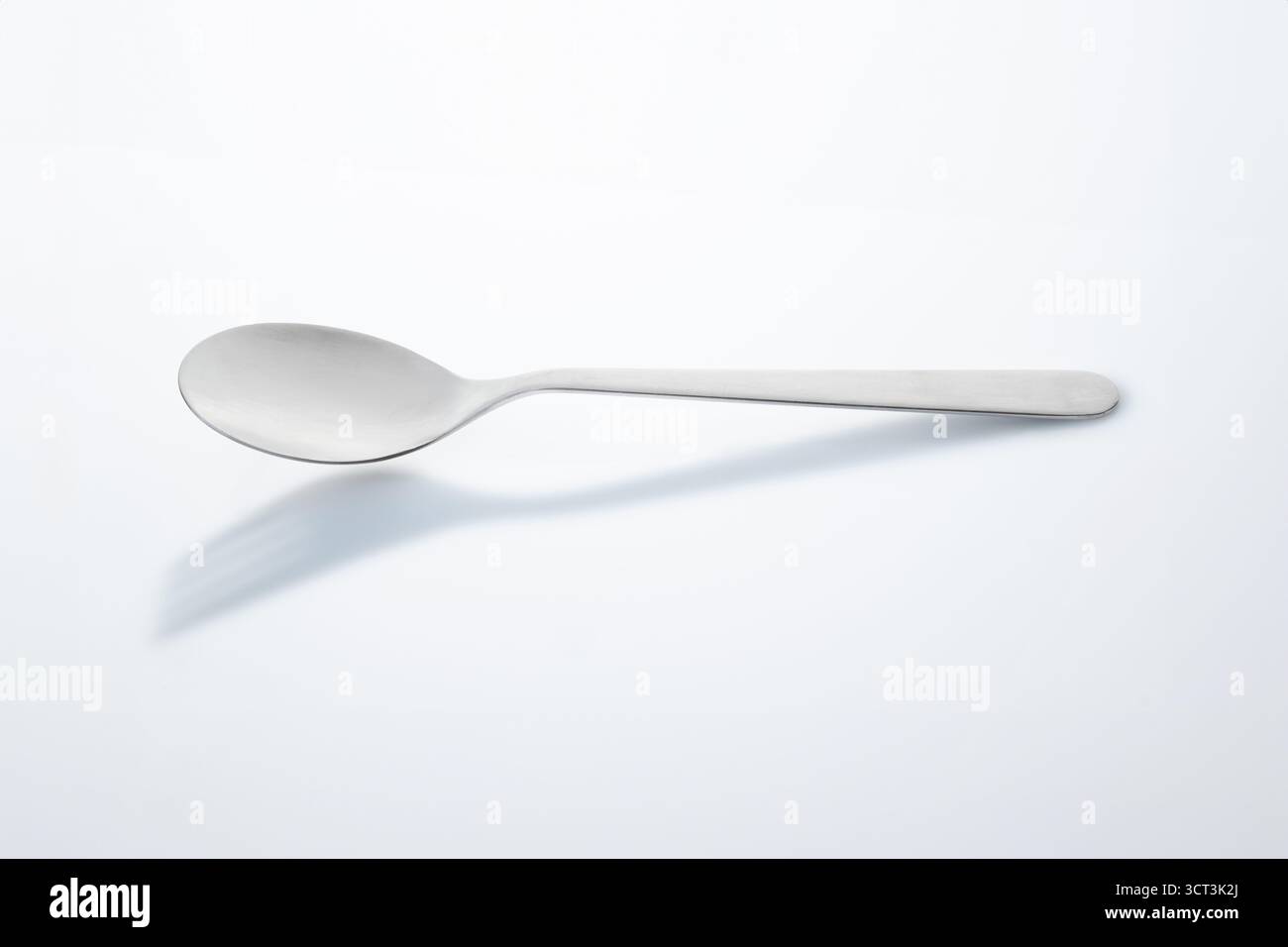 Löffel auf weißem Hintergrund mit Schirmgabel Stockfoto