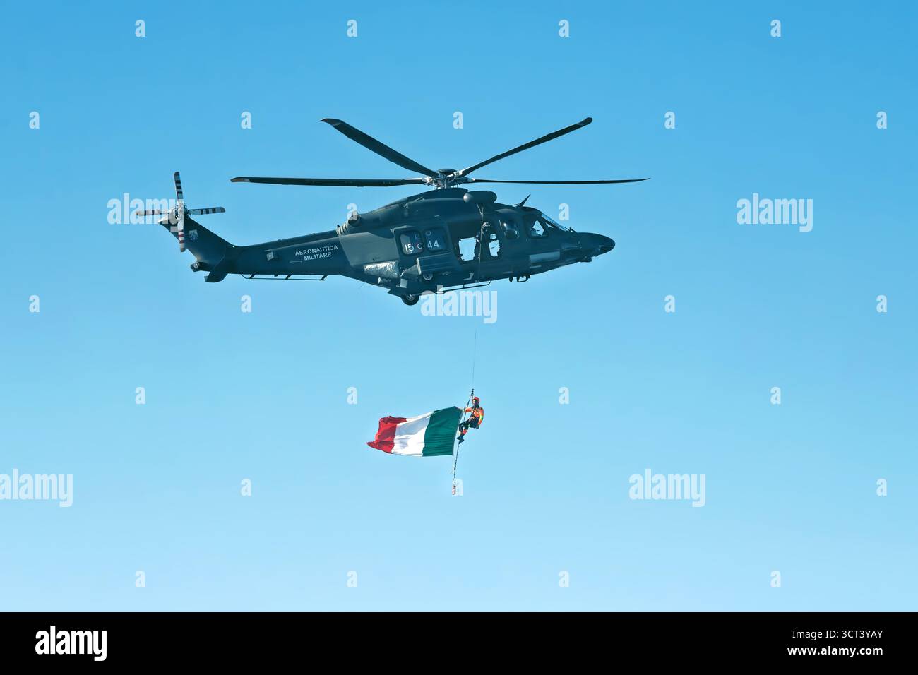 San Pawl, Malta - 09.29.2025: Hubschrauber der italienischen Luftwaffe trägt einen Soldaten und eine Nationalflagge in einer atemberaubenden Luftanlage. Stockfoto