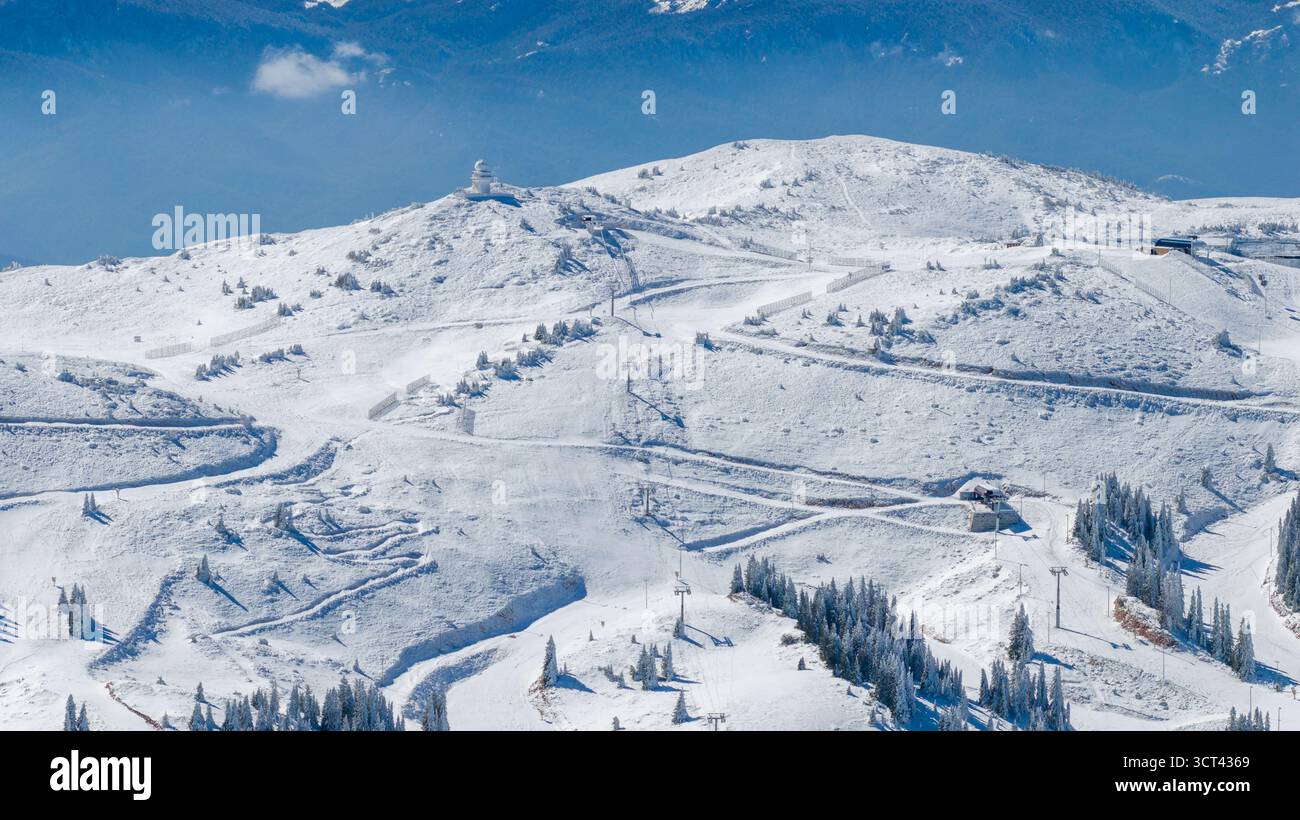 Breites Drohnenpanorama der schneebedeckten Bergkämme Jahorina, die Skipisten und Hochlandwälder unter klarem blauem Himmel enthüllen Stockfoto