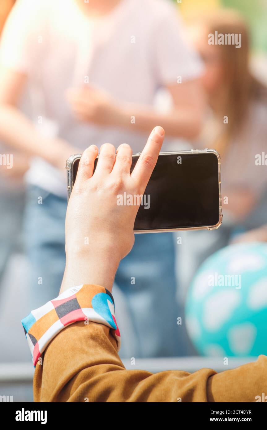 Eine Frau aus dem Publikum filmt eine Kinderveranstaltung auf einem Smartphone. Stockfoto