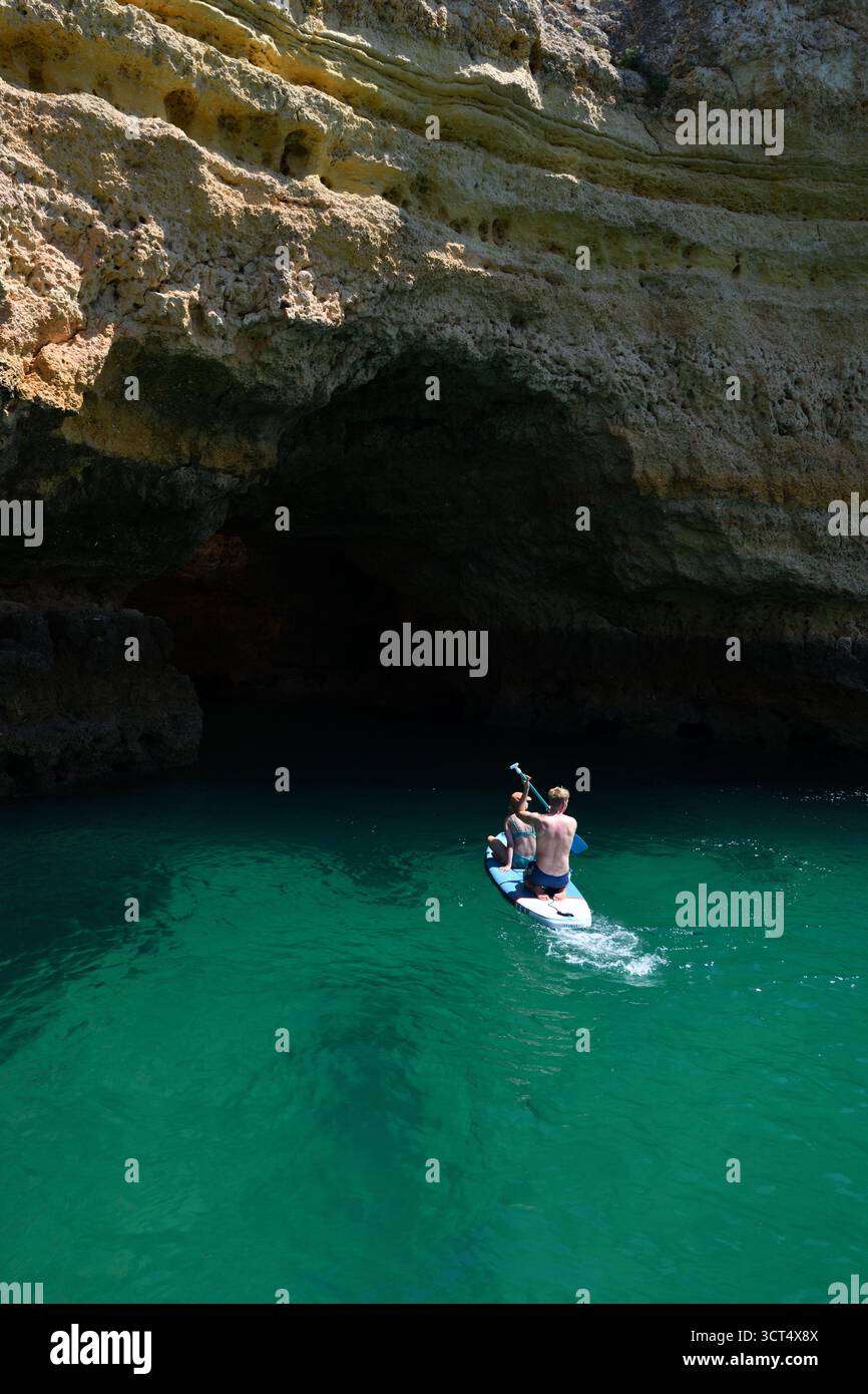 Paddelboarder erkunden eine der vielen Höhlen entlang der Algarve Küste in Portugal. Stockfoto
