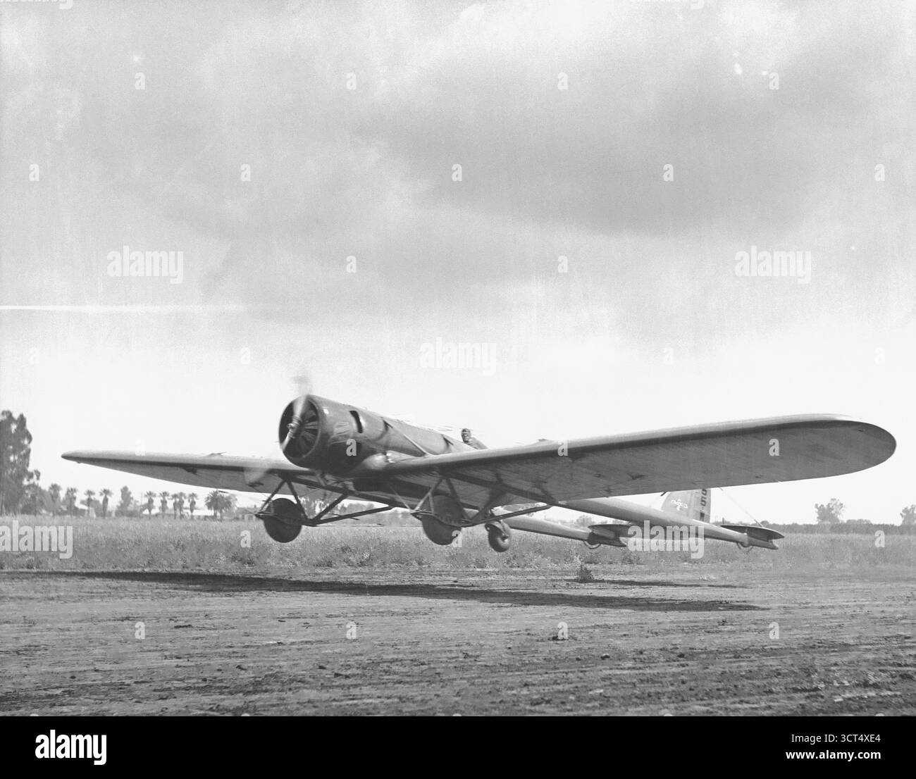 Einmotorige Oldtimerflugzeuge mit niedrigem Flügel, die von einem Schotterfeld starten Stockfoto