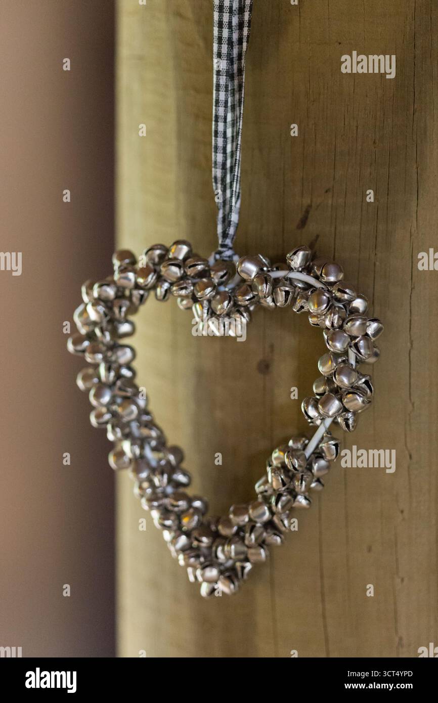 Ein dekoratives herzförmiges Ornament hängt an einem Holzbalken an einem Hochzeitsort und schafft ein romantisches und rustikales Detail Stockfoto