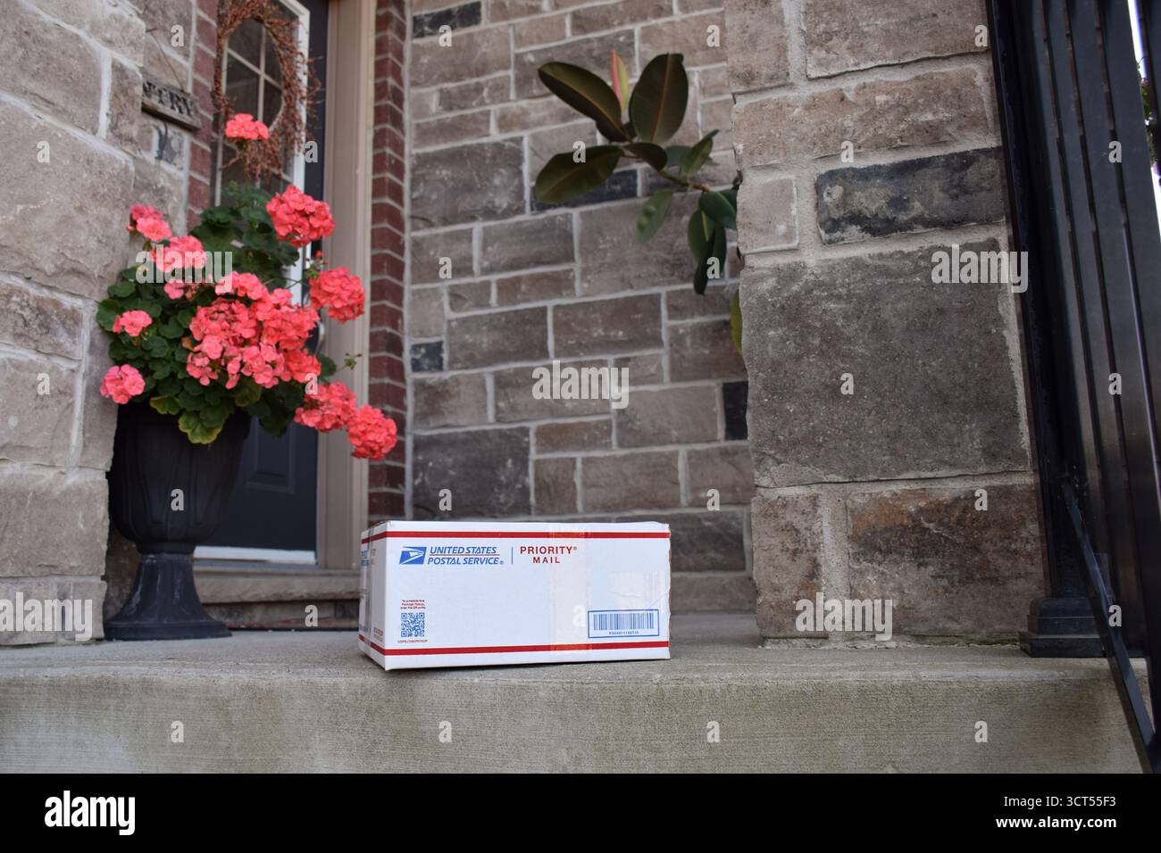 4. Oktober 2025: East Gwillimbury, Ontario, Kanada: Der United States Postal Service stellt eine Priority-Postverpackung auf der Veranda eines Wohnhauses auf Stockfoto