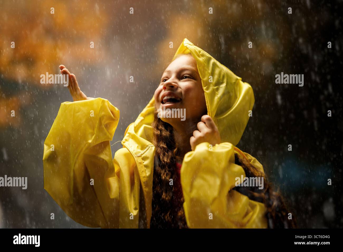 Glückliches kleines Mädchen im Regen auf einem Herbstspaziergang Stockfoto