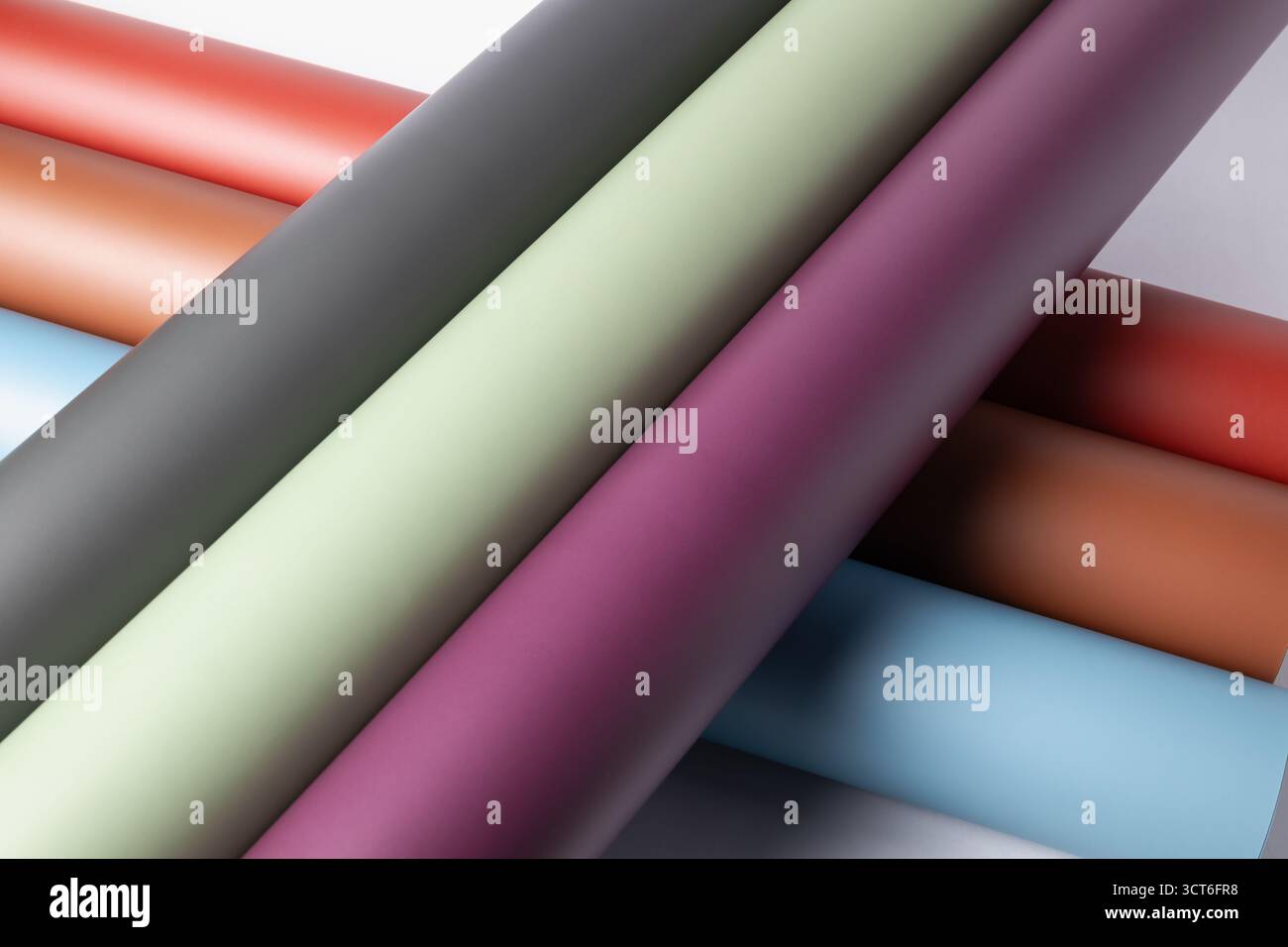 Gerollte matte Hintergrundpapierbögen für Fotografie oder Basteln: Tiefes Pflaumengrün, Salbeigrün, Grau, Rost und lebendiges Rot und Blau Stockfoto