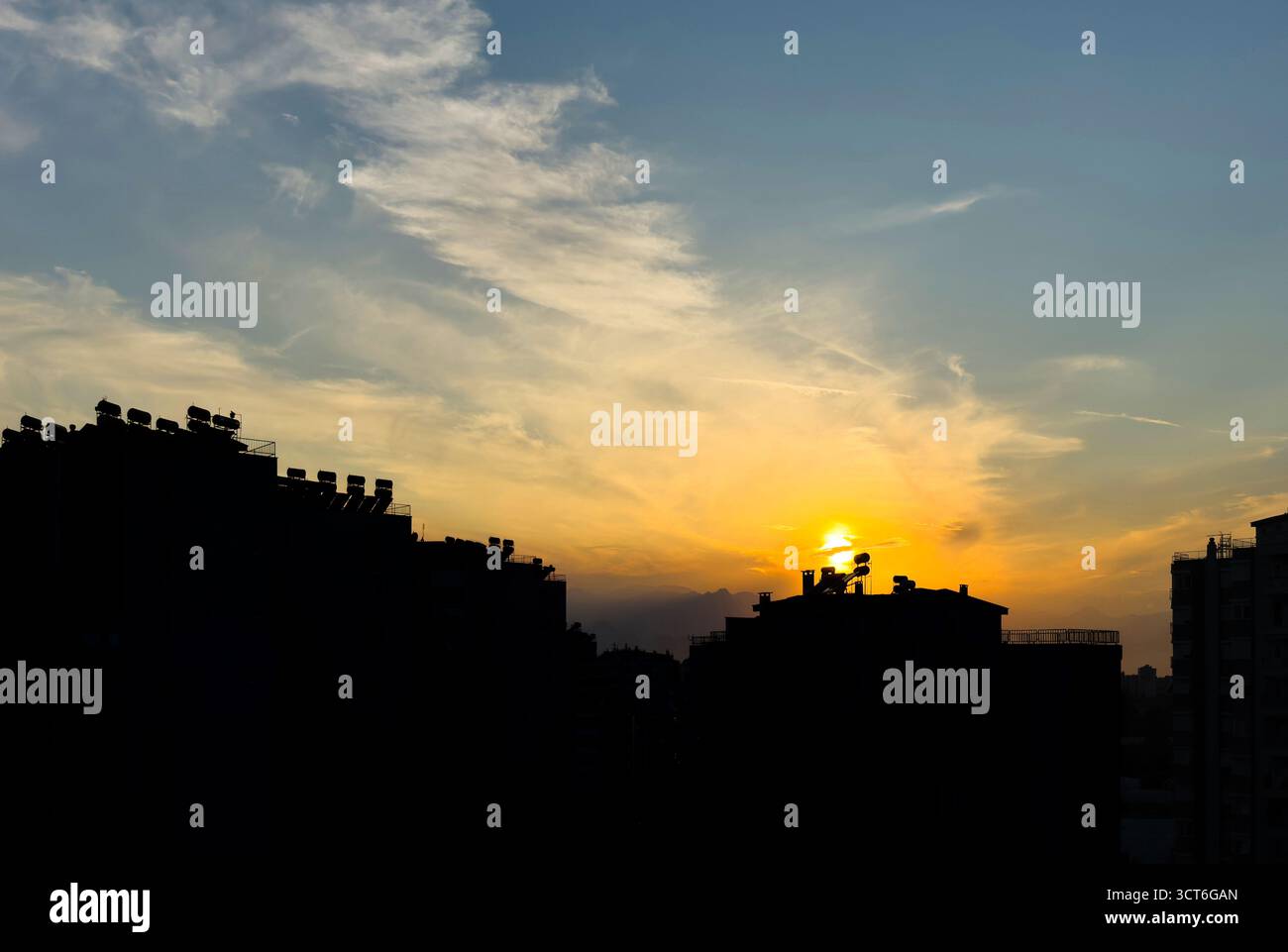 Sonnenuntergang über der Skyline der Stadt mit Silhouetten und warmem Himmel Stockfoto