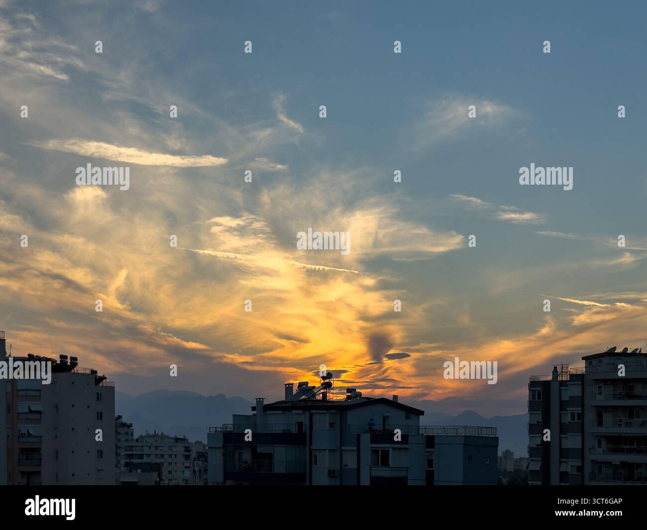Sonnenuntergang über der Skyline der Stadt mit Silhouetten und warmem Himmel Stockfoto