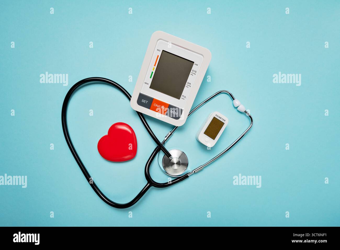 Stethoskop, Herzmodell, Pillen und digitale Geräte auf blassblauem Hintergrund symbolisieren Liebe und Pflege im medizinischen Bereich. Stockfoto