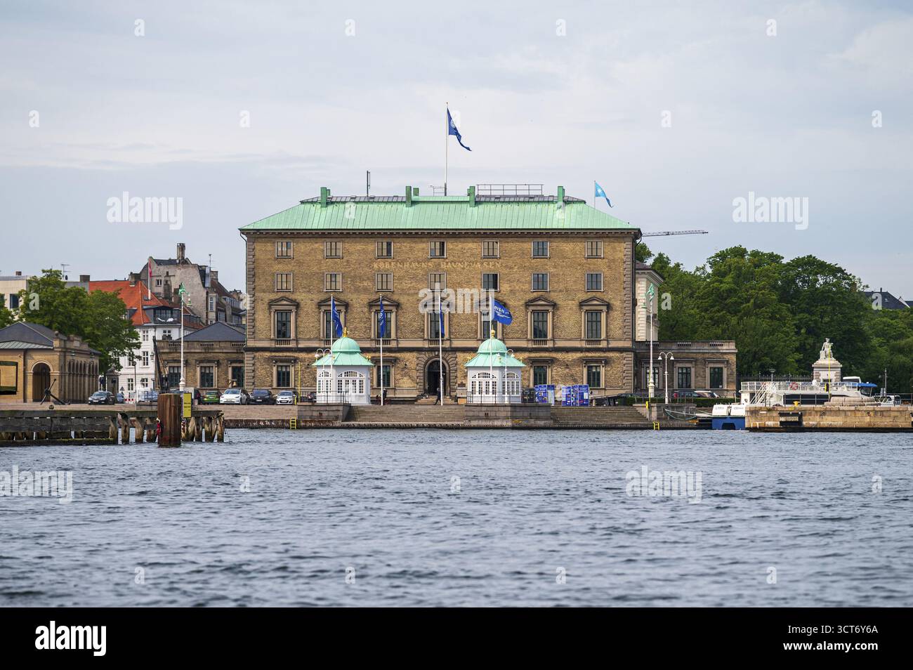 Historisches Gebäude mit Flaggen am Flussufer in klassischer Architektur, Kobenhavns Havns Pensionskasse, Kopenhagen, Dänemark Stockfoto
