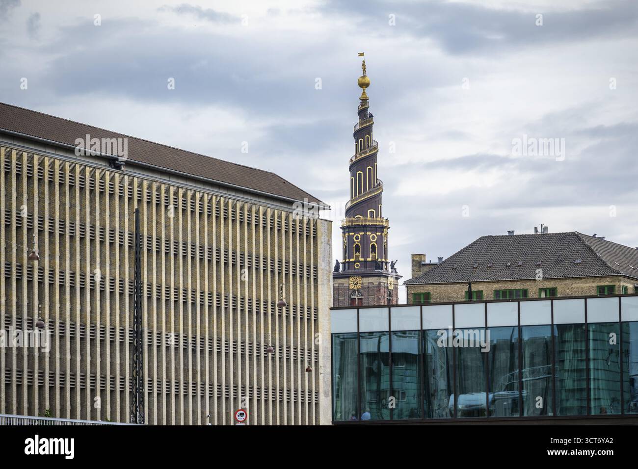 Historischer Turm neben modernen Gebäuden unter bewölktem Himmel in Kopenhagen, Korkenziehertreppe, Treppe zu Heven, vor Frelsers Kirke, Copenha Stockfoto