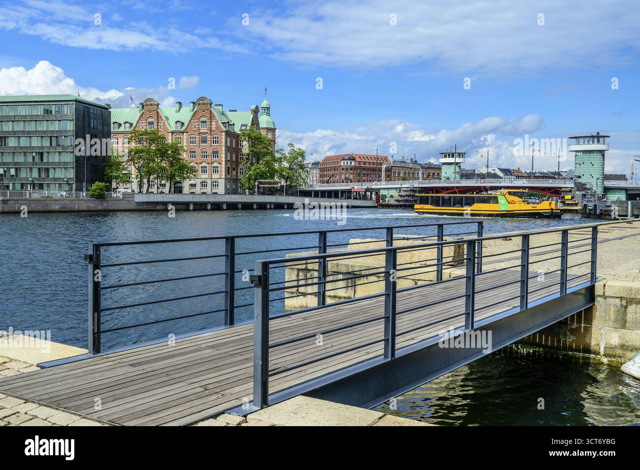 Klares blaues Wasser mit einer modernen Brücke und städtischen Gebäuden unter blauem Himmel, Christianshavn, Kopenhagen, Dänemark Stockfoto