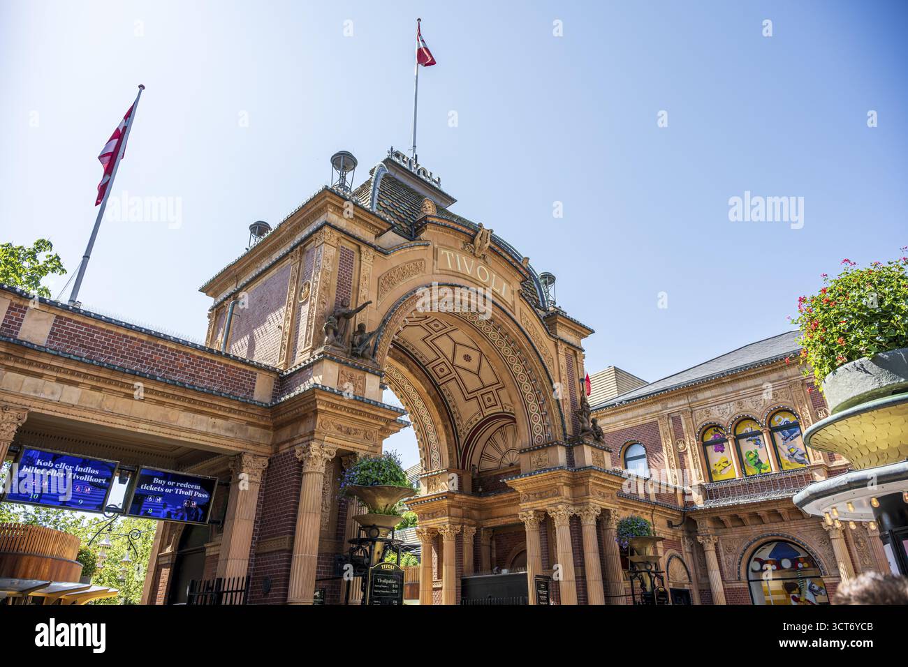 Dekoratives Eingangstor von Tivoli, eingerahmt von architektonischen Details und schwenkenden Fahnen vor einem klaren Himmel, Tivoli, Indre by, Kopenhagen Stockfoto