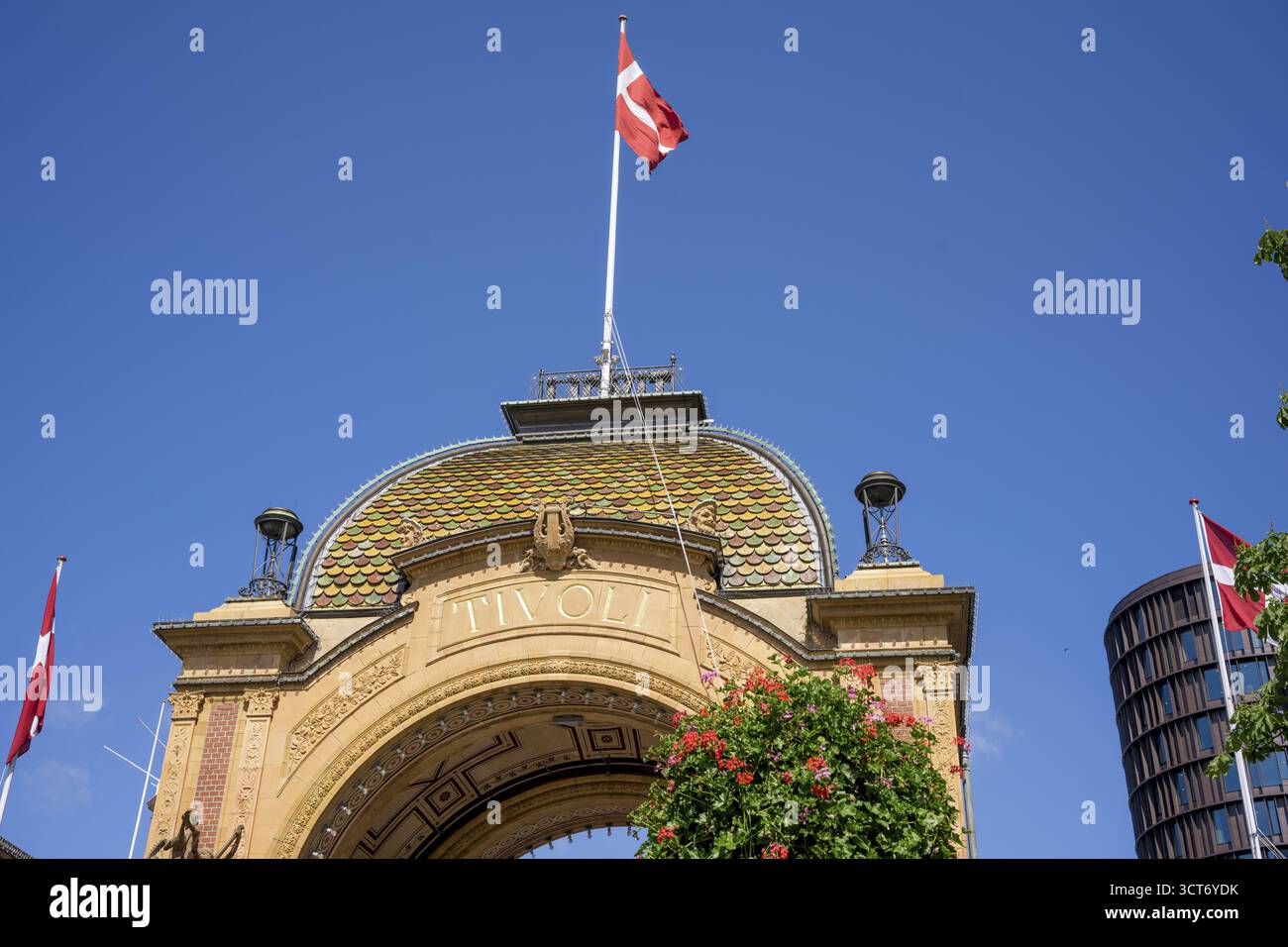 Eintritt zum Tivoli mit dänischer Flagge und dekorativen Blumen unter einem klaren blauen Himmel, Tivoli, Indre by, Kopenhagen Stockfoto