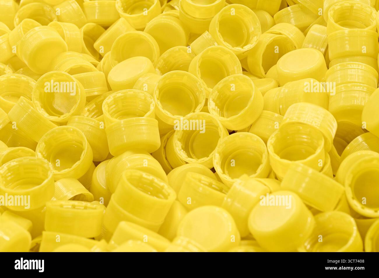 Viele gelbe Plastikflaschenverschlüsse, Nahaufnahme, abstrakter gelber Hintergrund Stockfoto