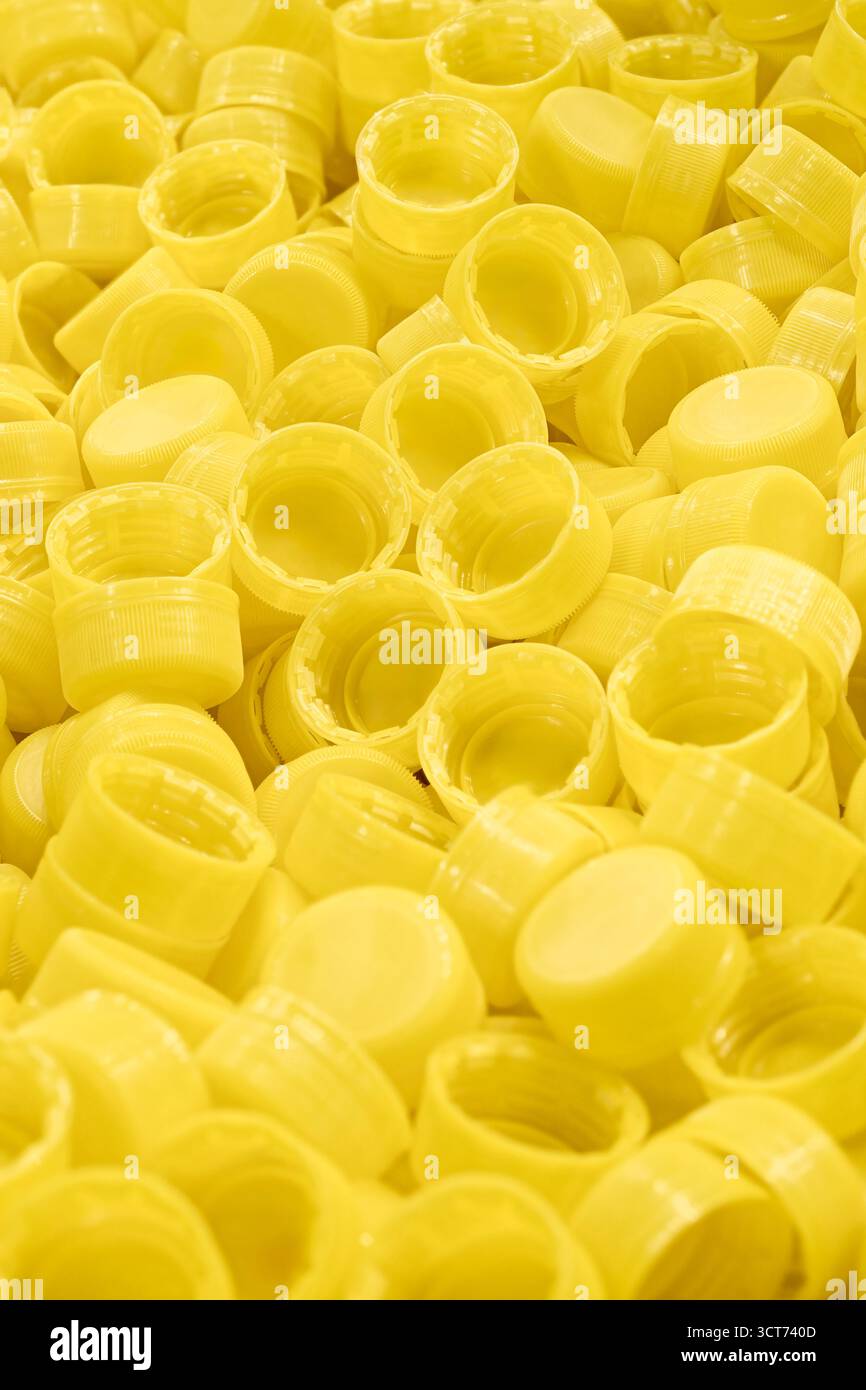 Viele gelbe Plastikflaschenverschlüsse, Nahaufnahme, abstrakter gelber Hintergrund Stockfoto