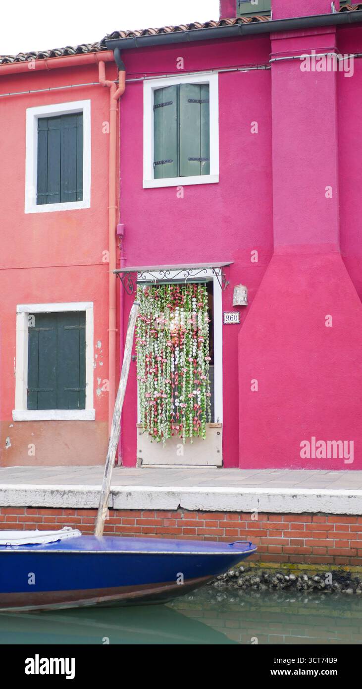 Vertikale Ansicht einer farbigen Wand und Häuser vor einem Kanal in Burano, Italien Stockfoto