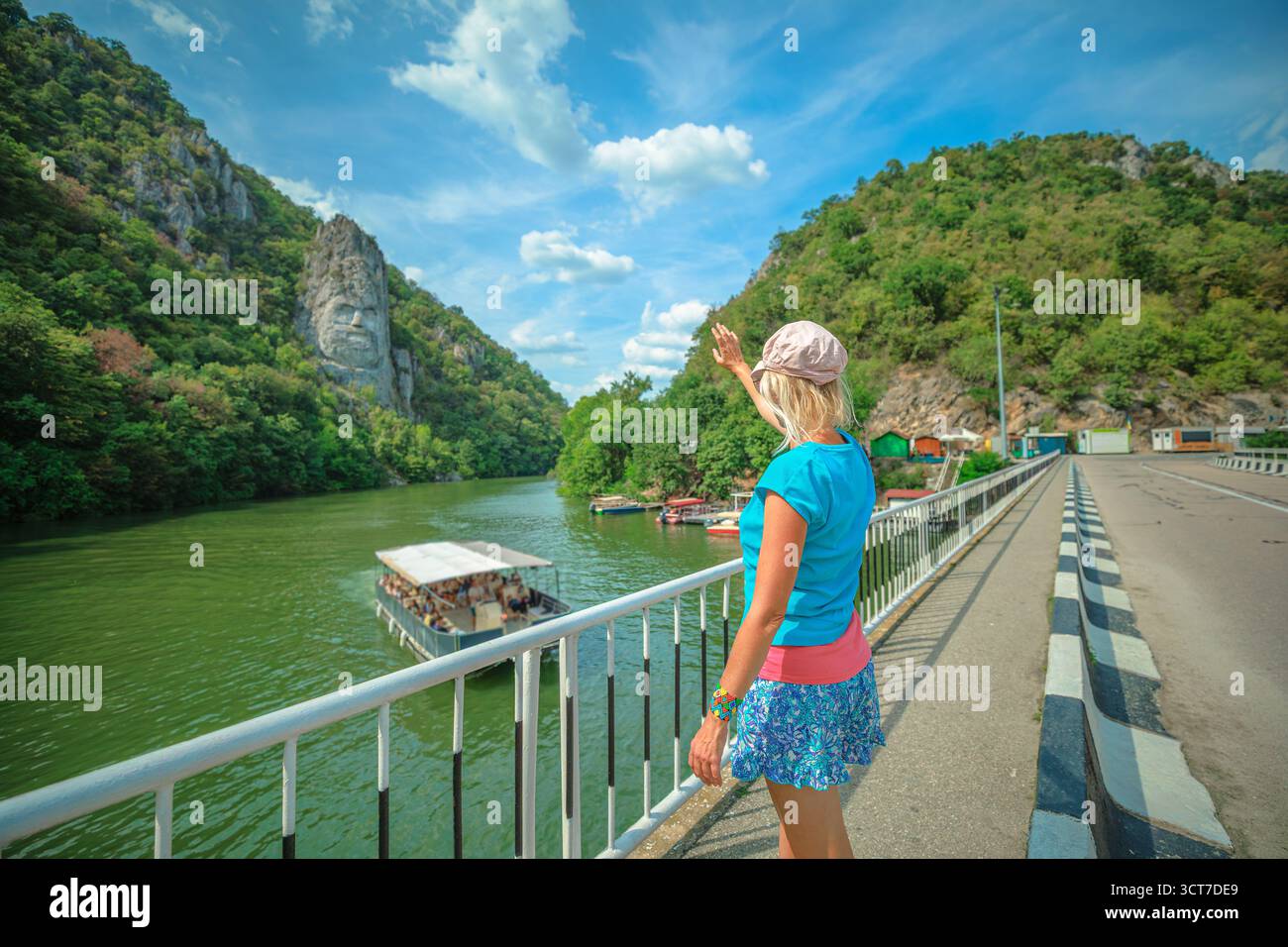 Frau steht auf einer felsigen Klippe mit Blick auf die weite Donauschlucht, üppige grüne Berge an der serbisch-rumänischen Grenze und genießt eine fantastische Flusslandschaft Stockfoto