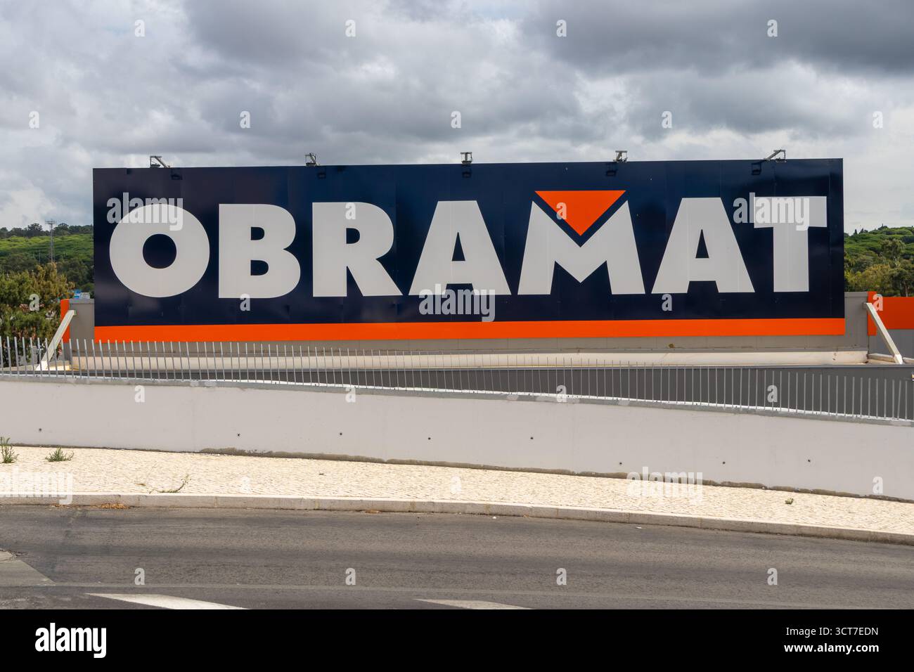 Ein großes, obramattes Schild im Freien, das auf ein Baustoffgeschäft in portugal unter bewölktem Himmel hinweist Stockfoto