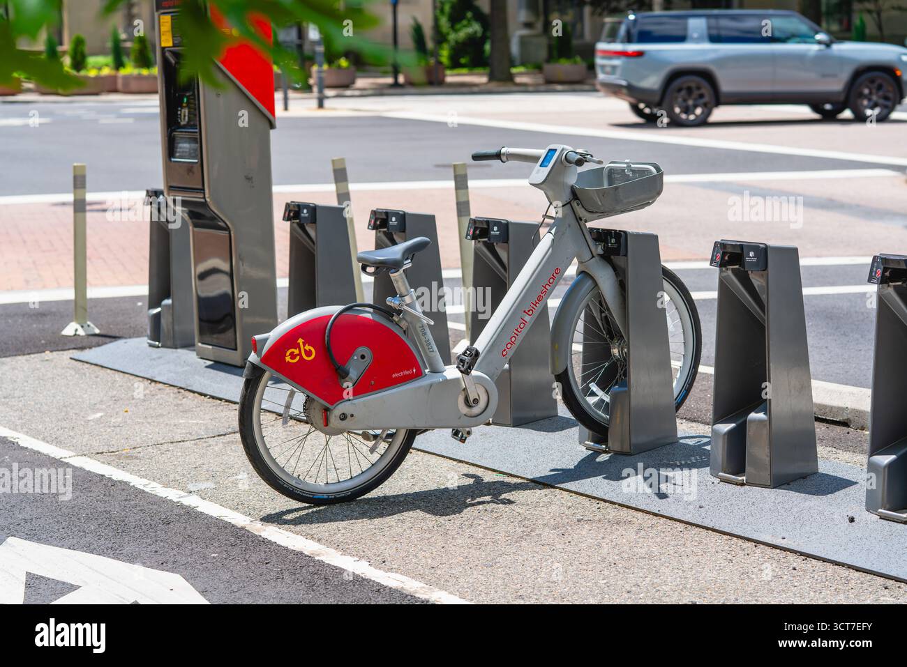 Washington D.C., USA - 24. Mai 2025. Ein einzelnes elektrisches Capital Bikeshare-Fahrrad ruht in der Dockingstation neben einer ruhigen Kreuzung. Stockfoto