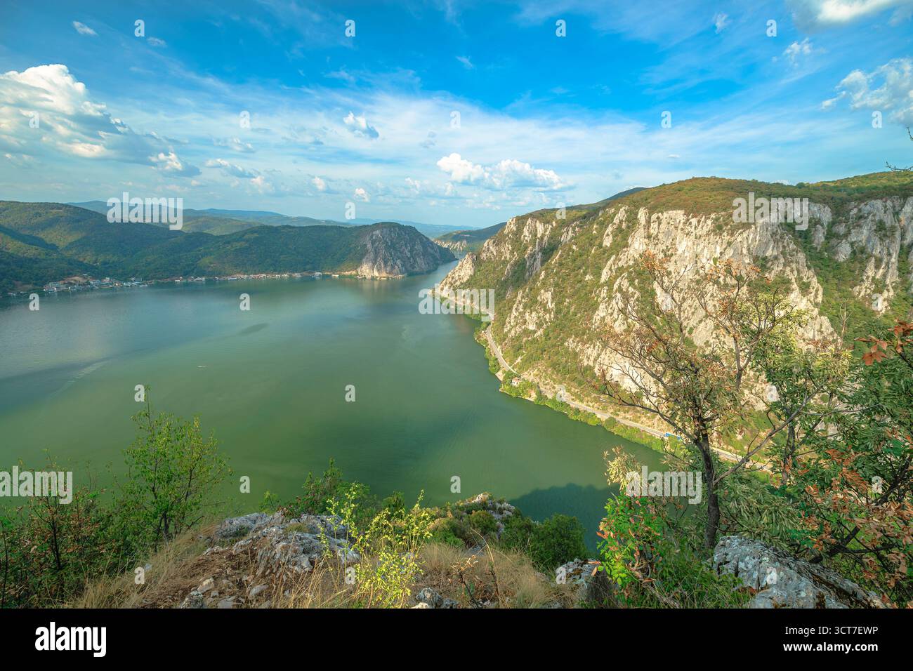Eine tiefe Donauschlucht durchzieht die Karpaten und trennt Serbien und Rumänien. Die steilen Hänge, die von grünen Wäldern bedeckt sind, ragen unter eine helle, wolkenlose Oberfläche Stockfoto
