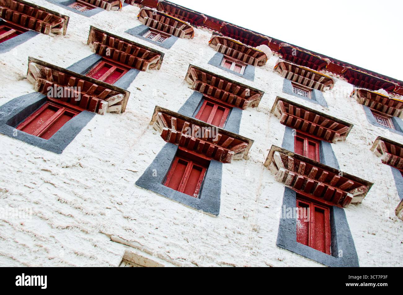 Traditionelle tibetische Architektur mit roten Fenstern und komplizierten Holzrahmen auf weiß getünchter Klostermauer mit einzigartiger geometrischer Symmetrie und de Stockfoto