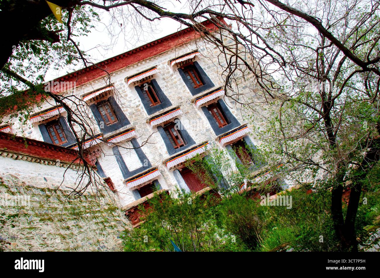 Traditionelle tibetische Architektur mit roten Fenstern und komplizierten Holzrahmen auf weiß getünchter Klostermauer mit einzigartiger geometrischer Symmetrie und de Stockfoto
