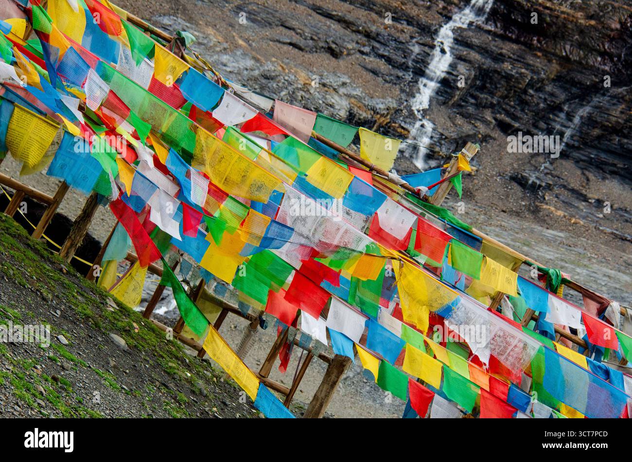 Farbenfrohe tibetische Gebetsfahnen flattern im Wind auf einem hohen Bergpass und symbolisieren Frieden, Spiritualität und Segen für alle. Stockfoto