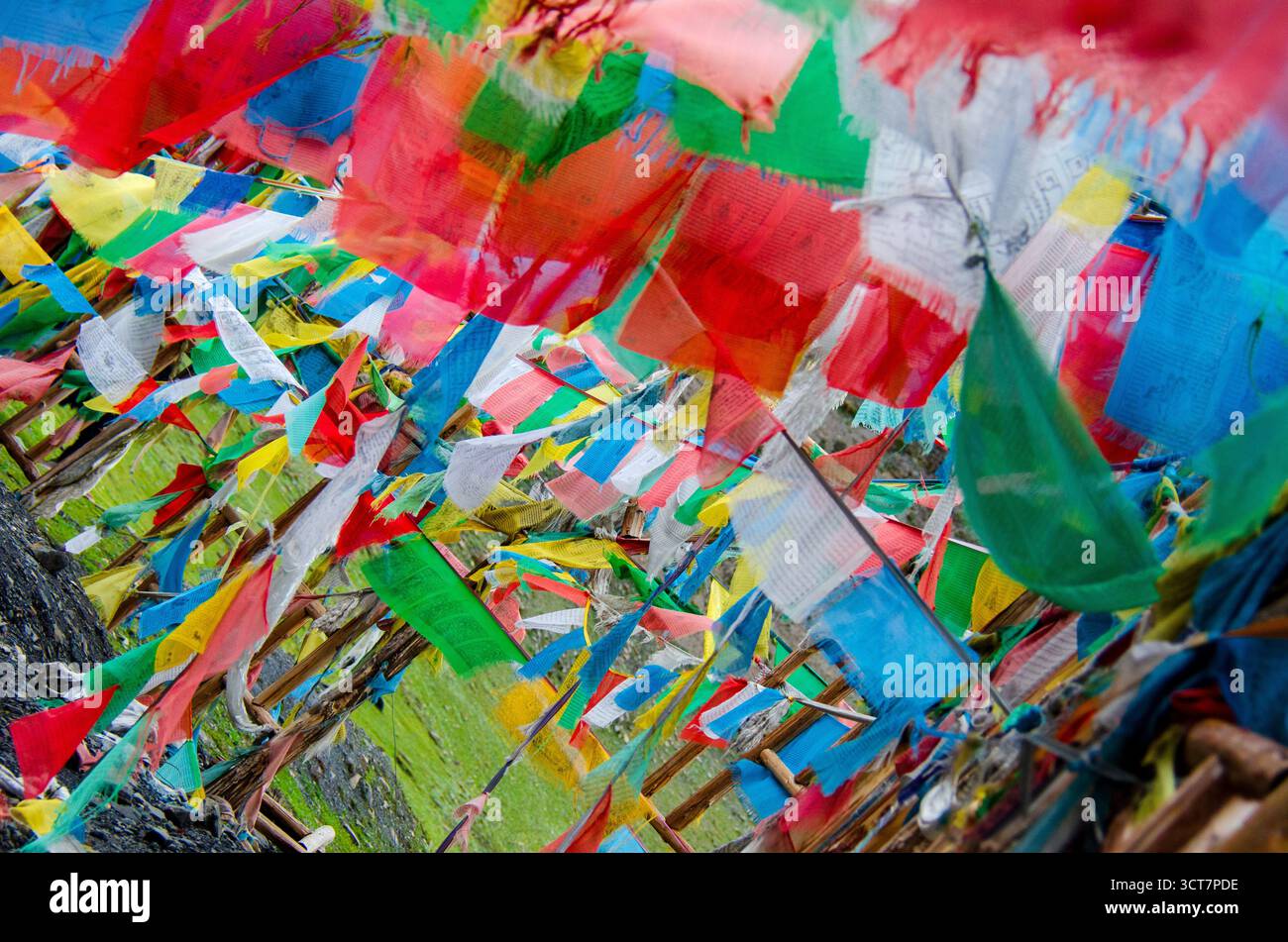 Farbenfrohe tibetische Gebetsfahnen flattern im Wind auf einem hohen Bergpass und symbolisieren Frieden, Spiritualität und Segen für alle. Stockfoto