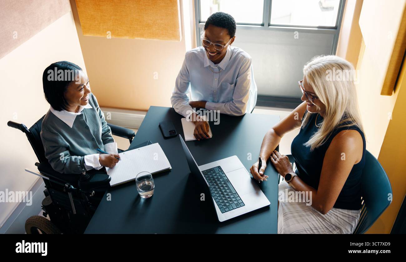 Eine vielfältige Gruppe von Fachleuten, darunter Rollstuhlfahrer, die ein produktives Meeting in einem Büro abhalten. Stockfoto